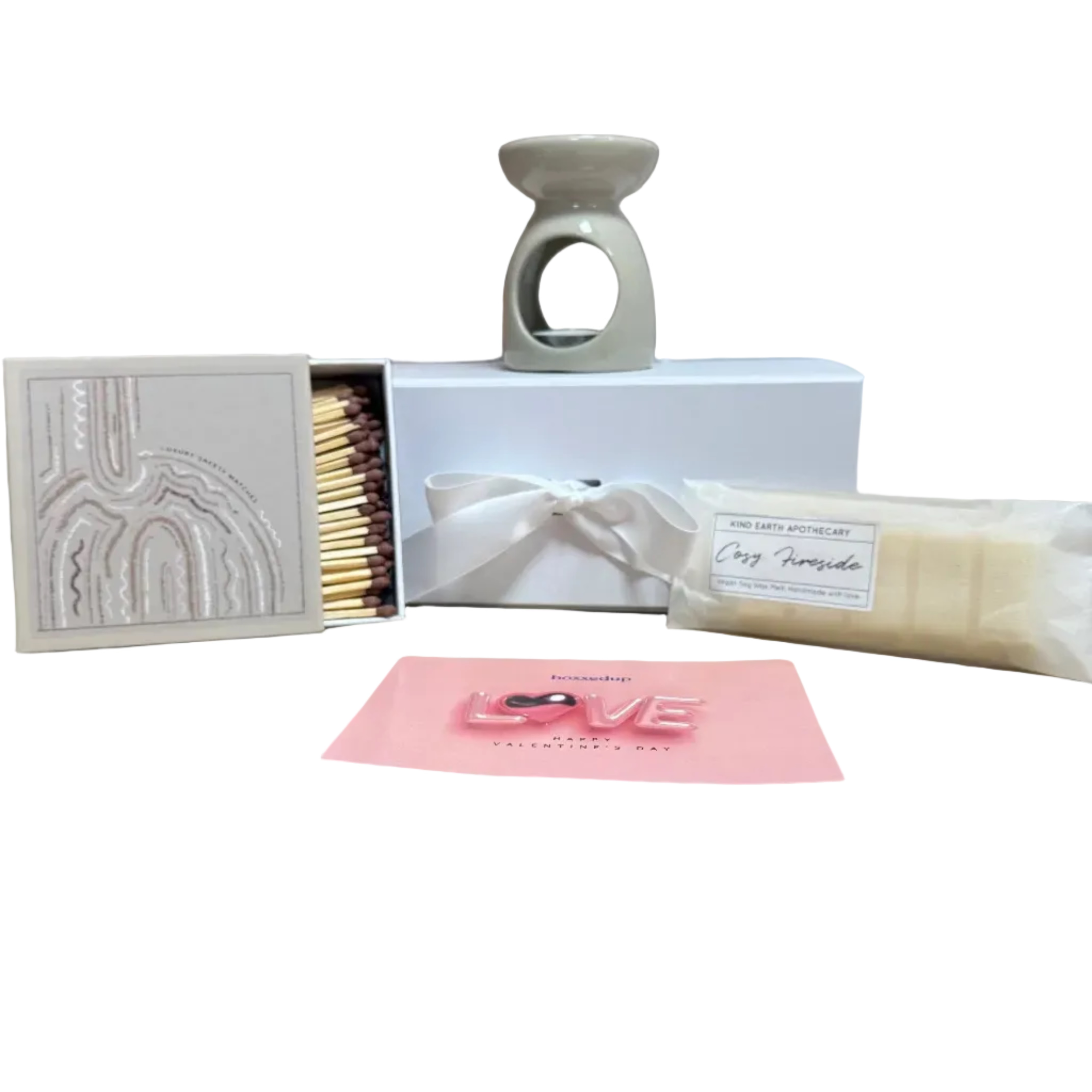 Matches, a small candle, and a bar of soap on a wooden surface with a brick wall background.