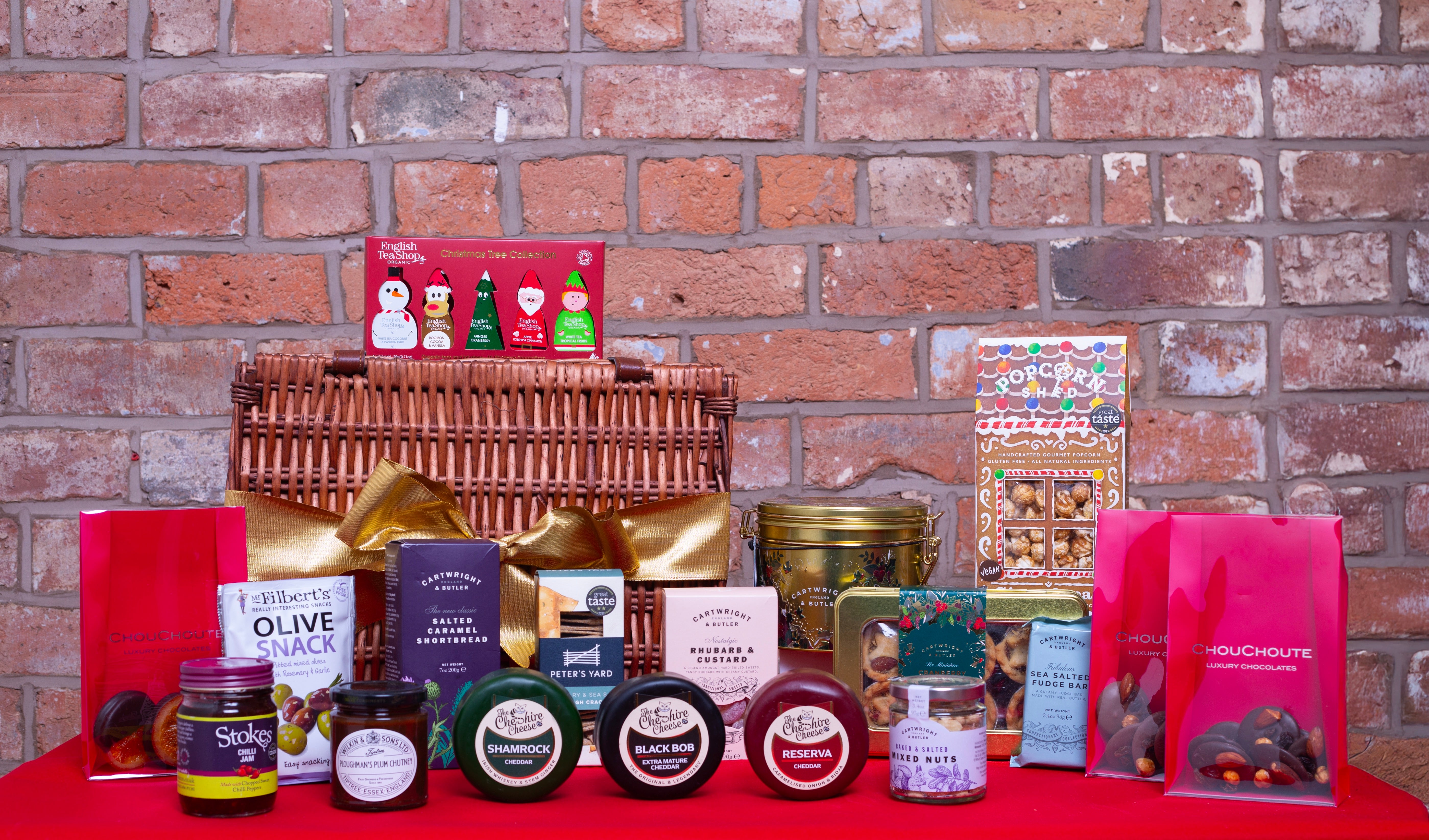 Christmas food hamper - Assorted gourmet food items and products displayed in front of a brick wall.