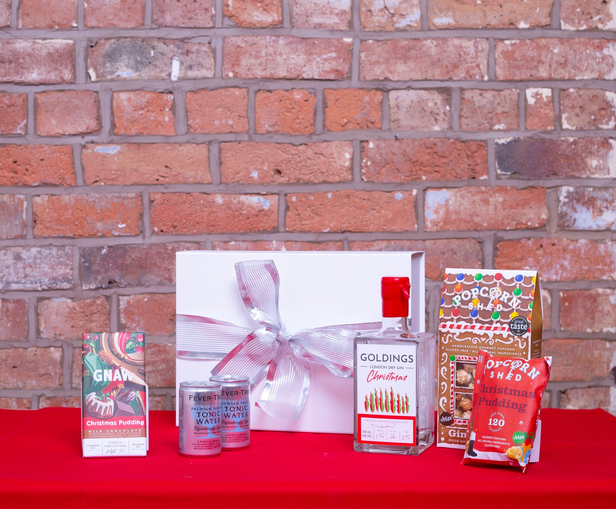 White gift box with silver ribbon gin bottle tonic and Christmas sweet items