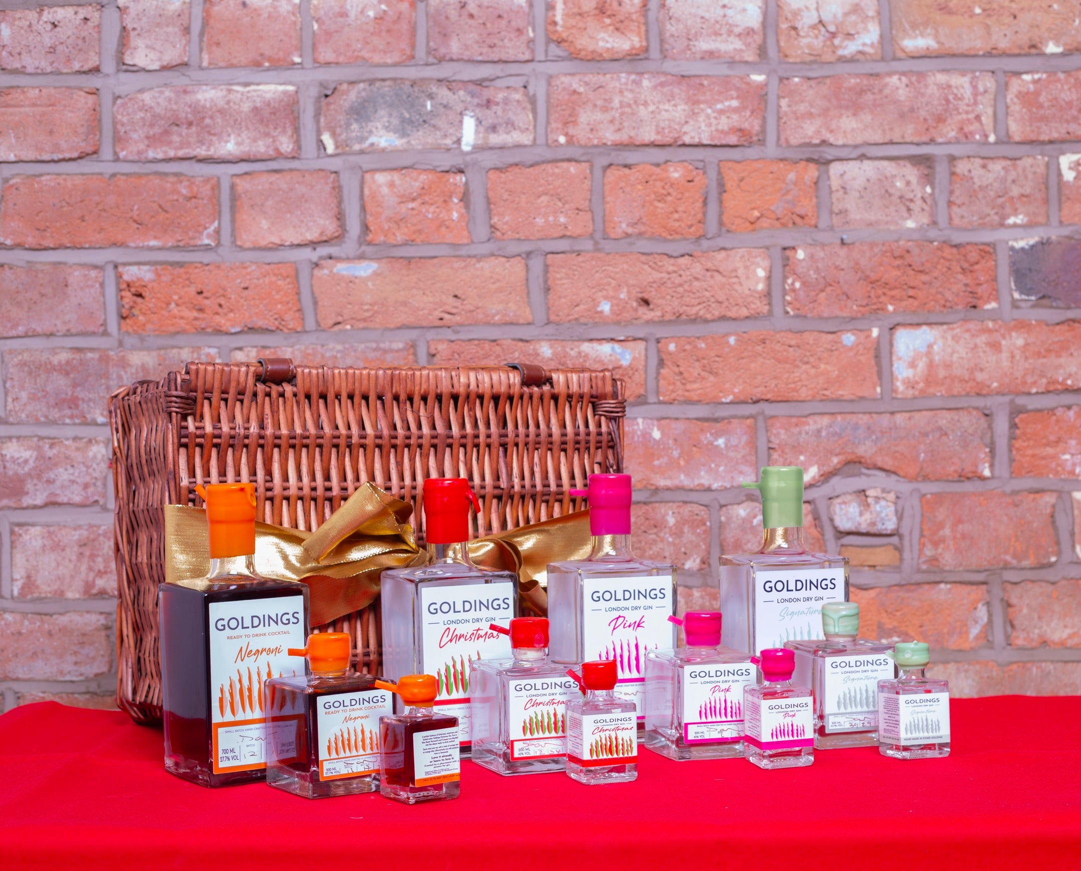 Collection of Goldings Gin products on a red surface with a brick wall background