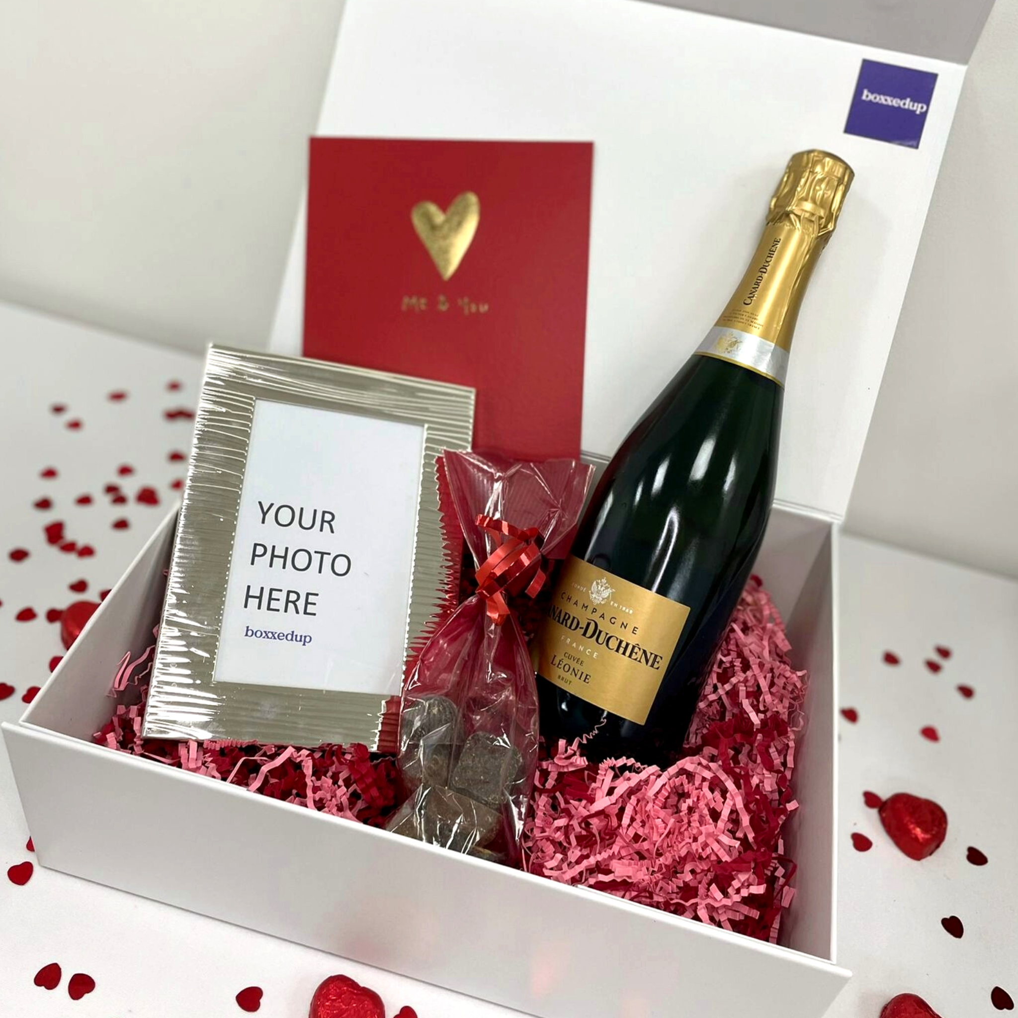 A box with valentine gifts, champagne, photo frame and card